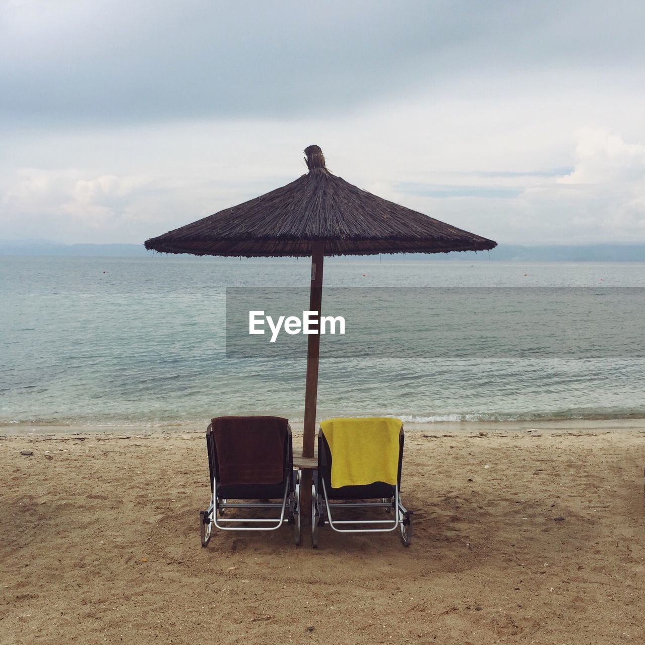 Chair on beach by sea against sky