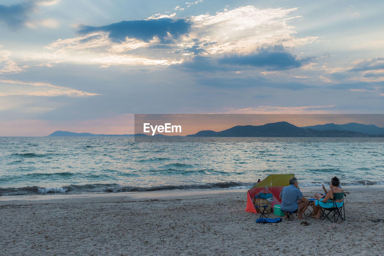 TOURISTS SITTING ON BEACH