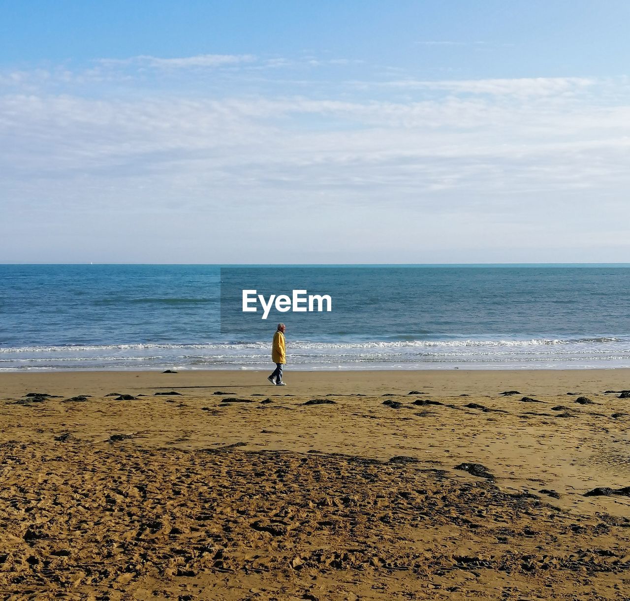 Senior man walking on beach against sky