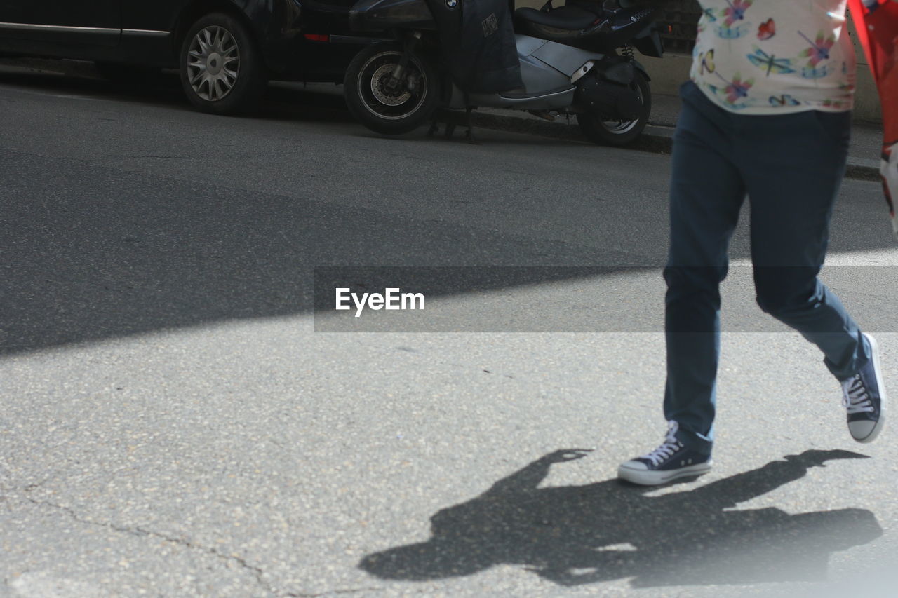 LOW SECTION OF WOMAN WALKING ON ROAD