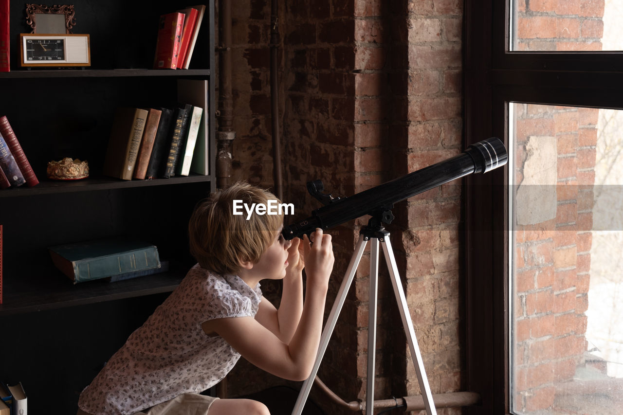 Side view of girl looking through telescope