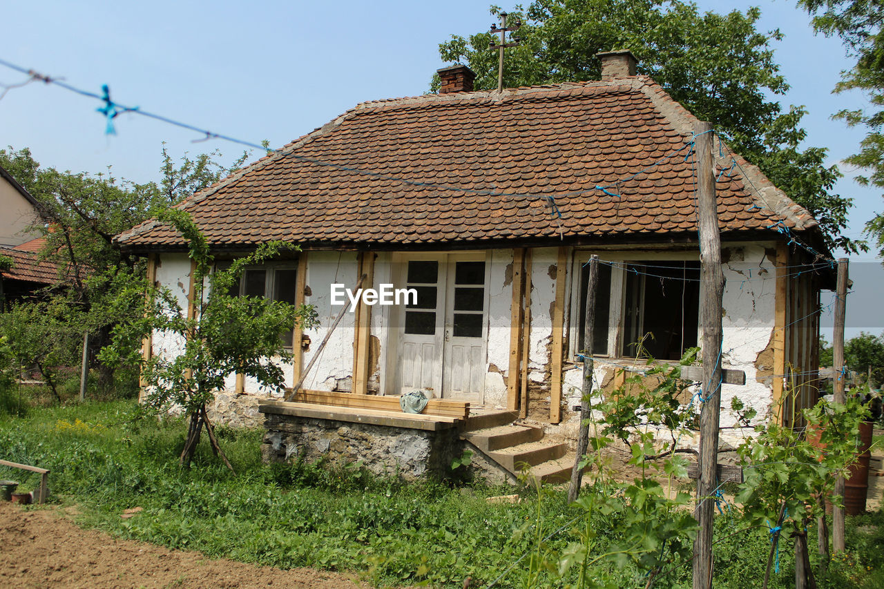 Old house by building against sky