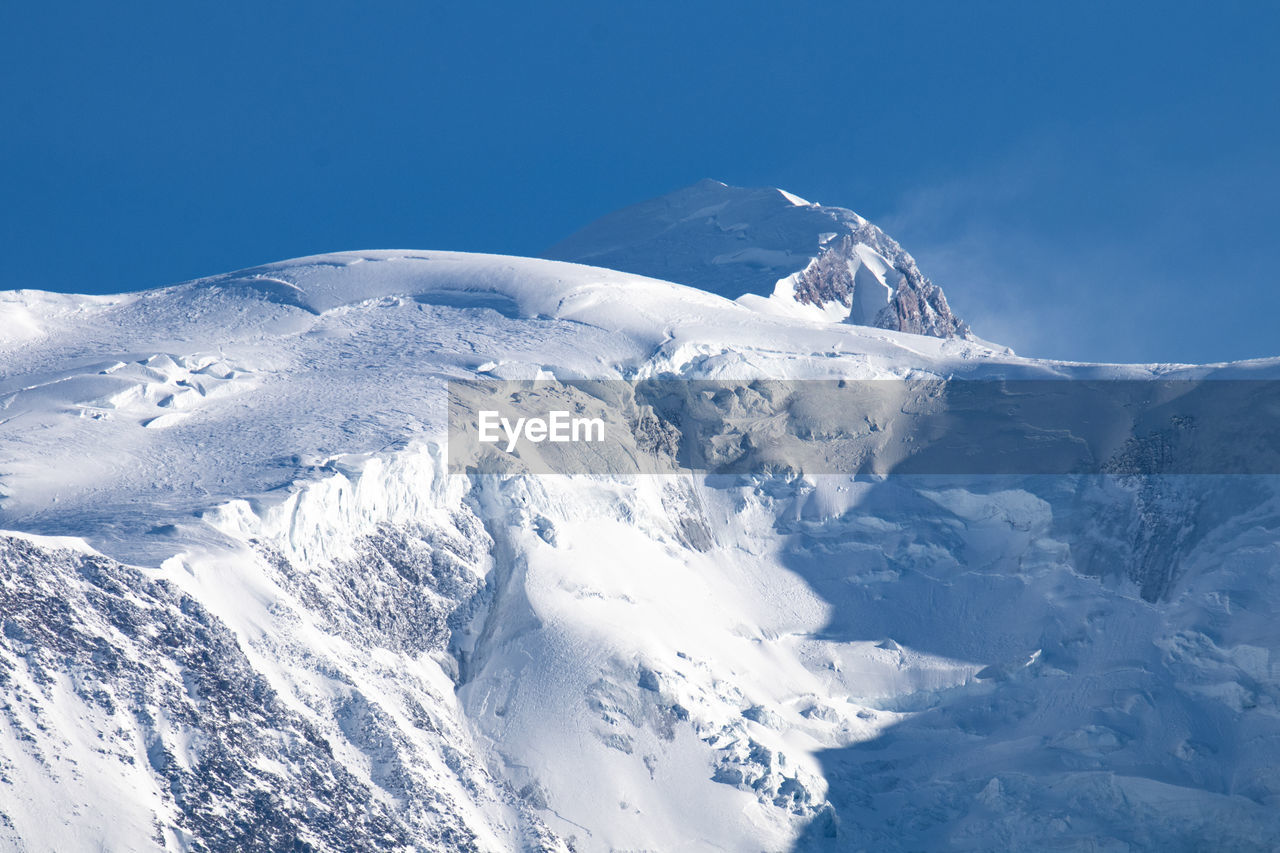 Scenic view of snowcapped mountains against clear blue sky