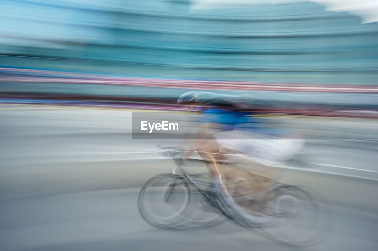 Blurred motion of man riding bicycle on street in city