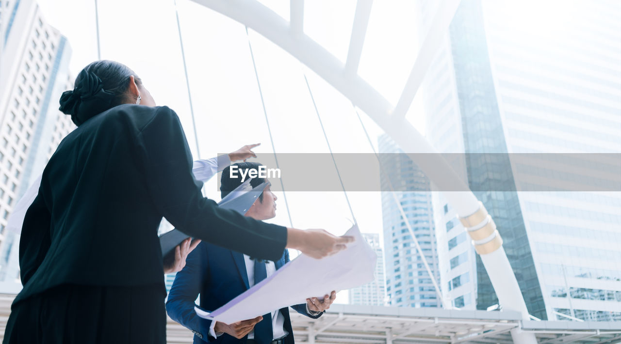 Business colleagues looking at buildings while standing in city