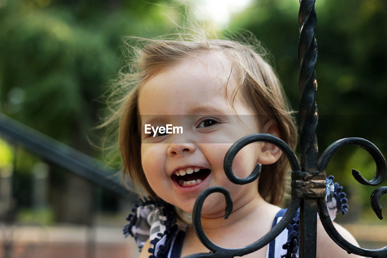 Portrait of cute girl smiling while standing by railing