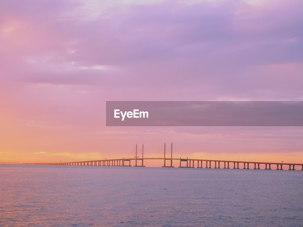 VIEW OF BRIDGE OVER SEA AGAINST SKY DURING SUNSET