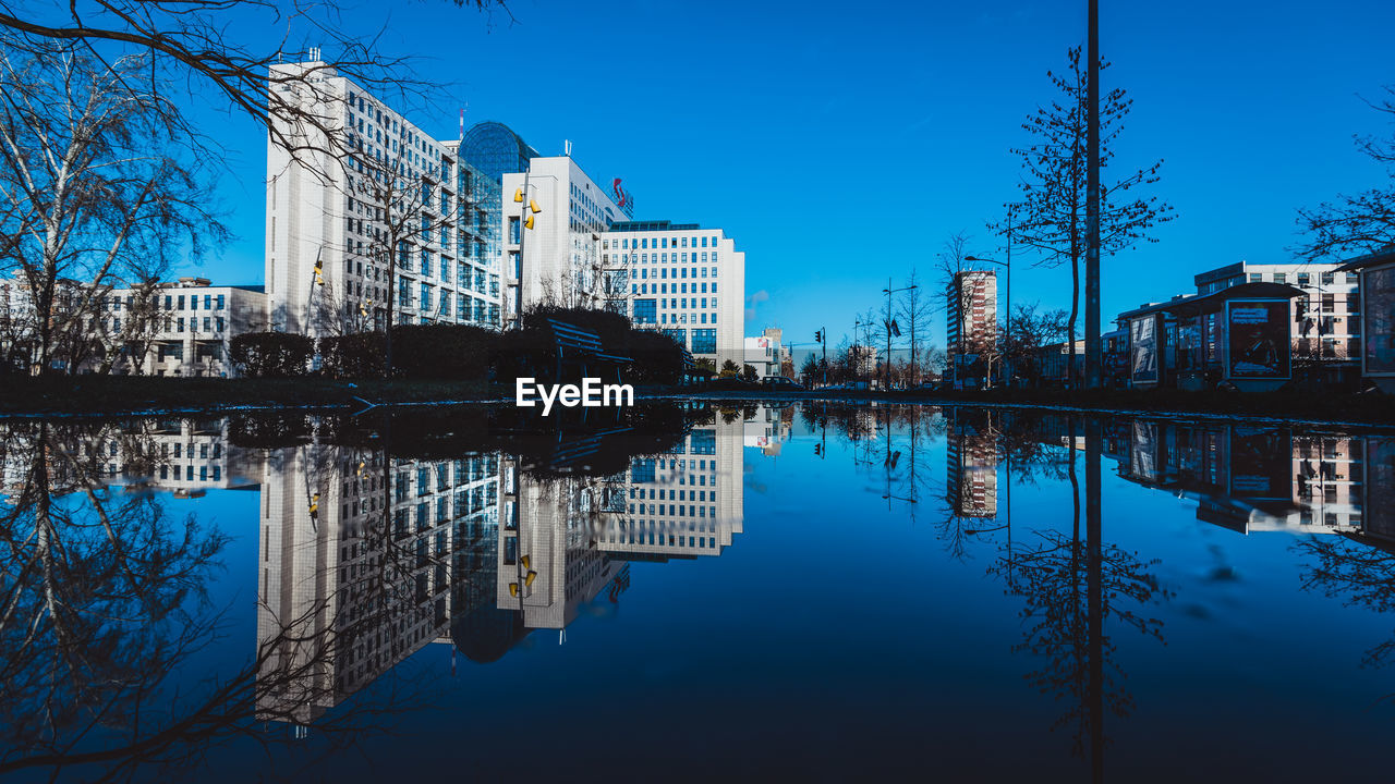 Reflection of buildings in lake against blue sky