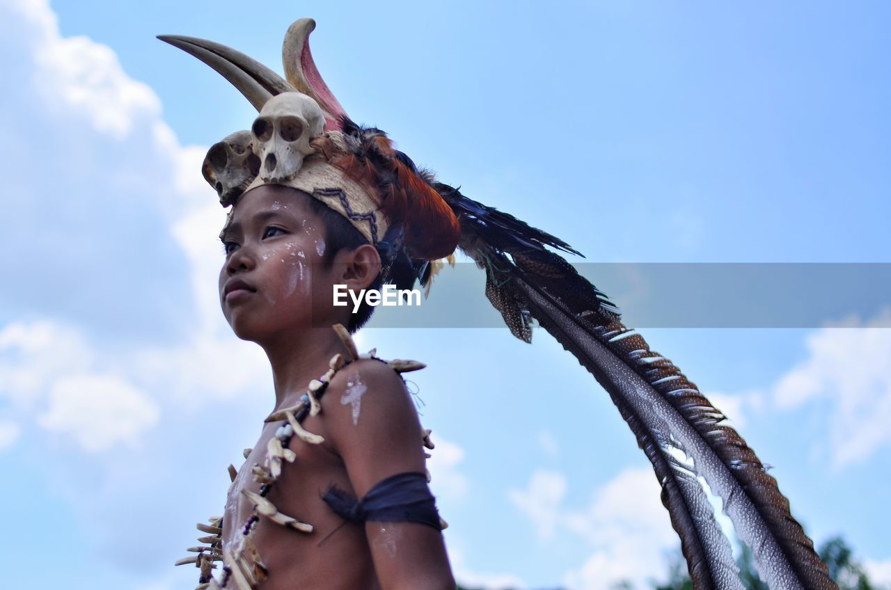 Low angle view of boy wearing headdress against sky