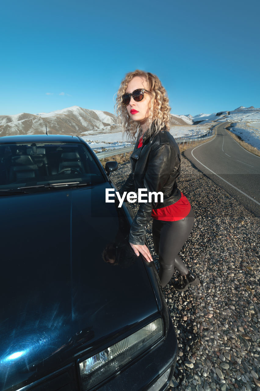 Young woman standing by car