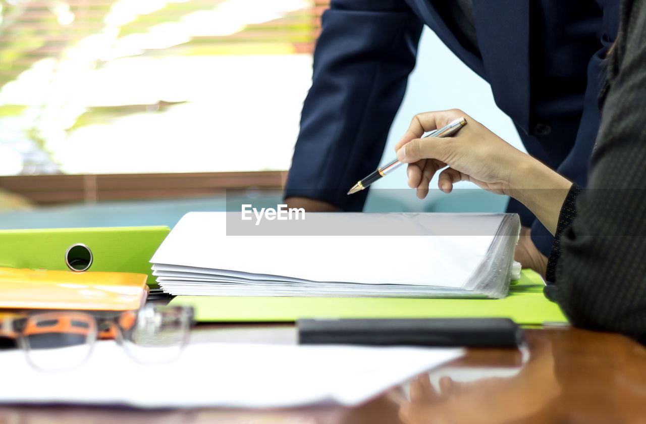 Midsection of colleagues discussing at desk in office