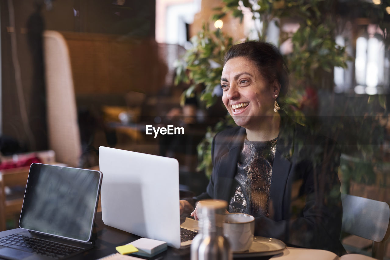 Smiling businesswoman using laptop in cafe