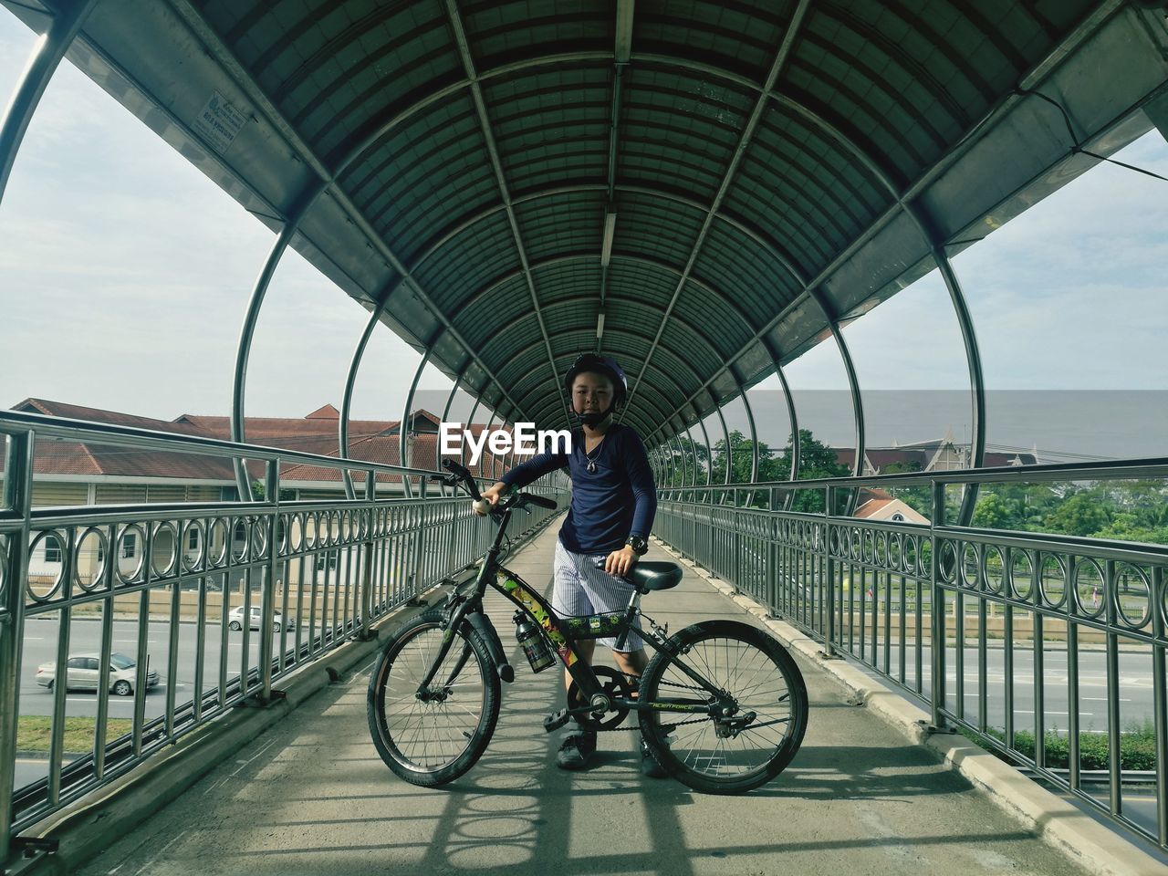 FULL LENGTH PORTRAIT OF MAN RIDING BICYCLE ON FOOTBRIDGE