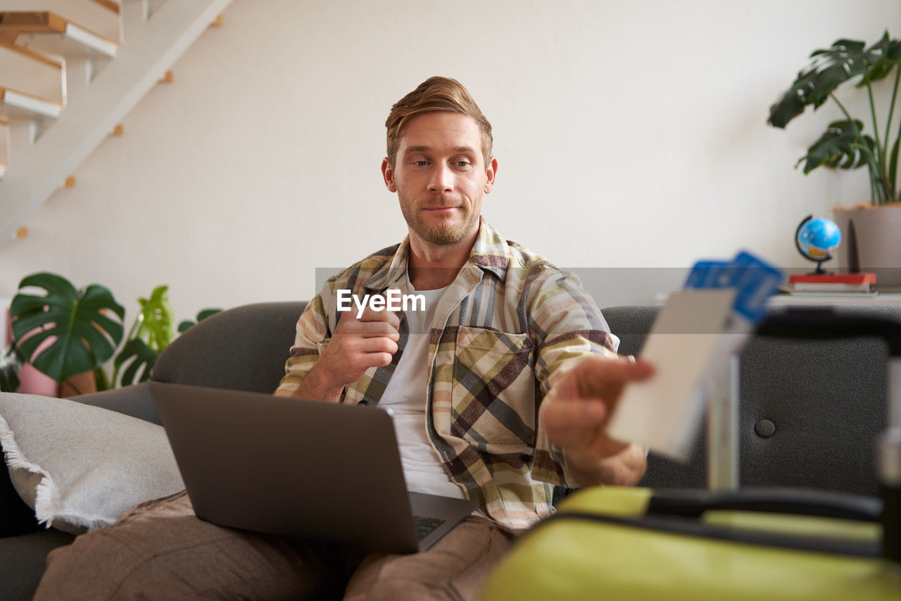 portrait of young man using laptop while sitting at home
