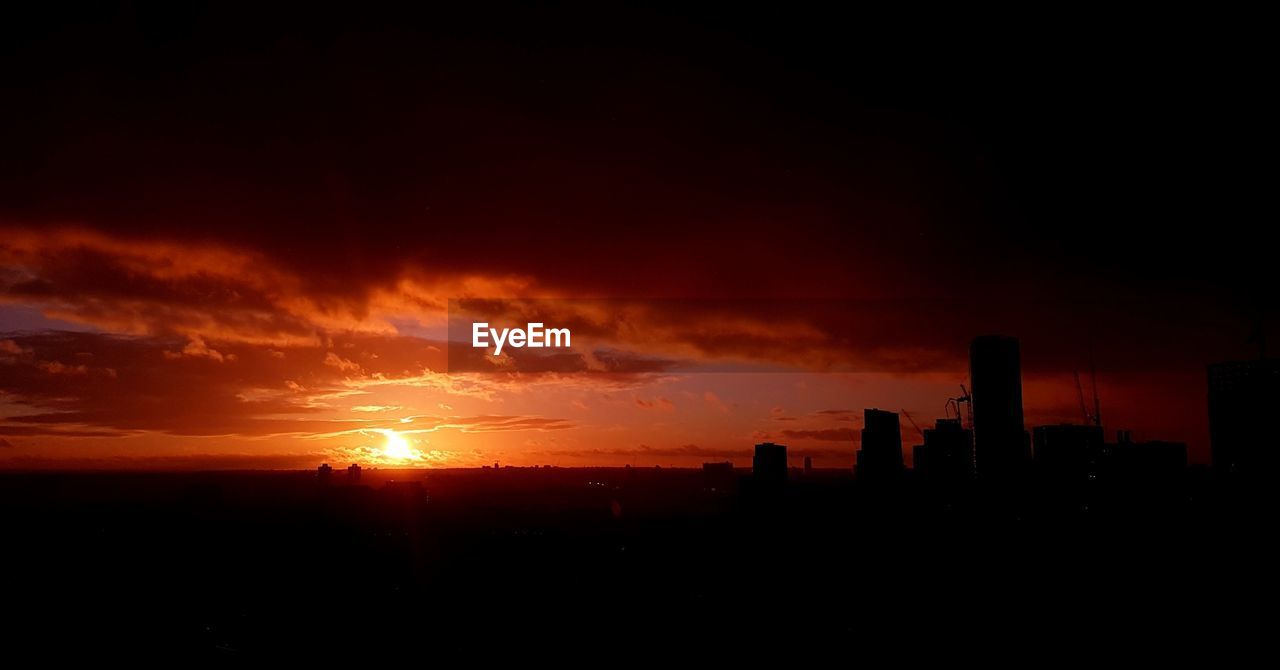 Silhouette of city against sky during sunset