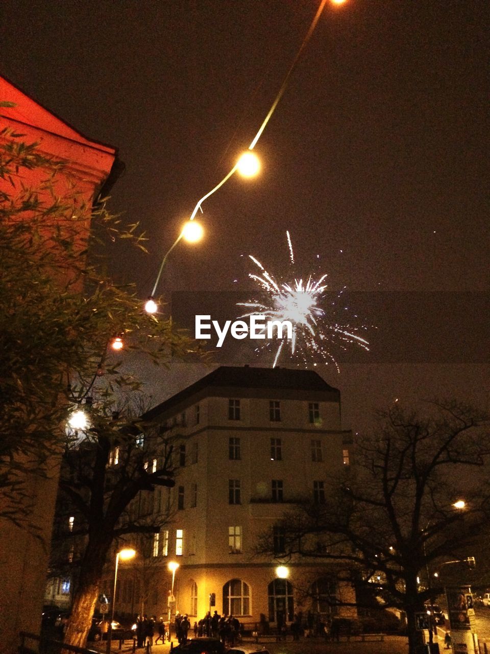 LOW ANGLE VIEW OF FIREWORK DISPLAY IN CITY AT NIGHT