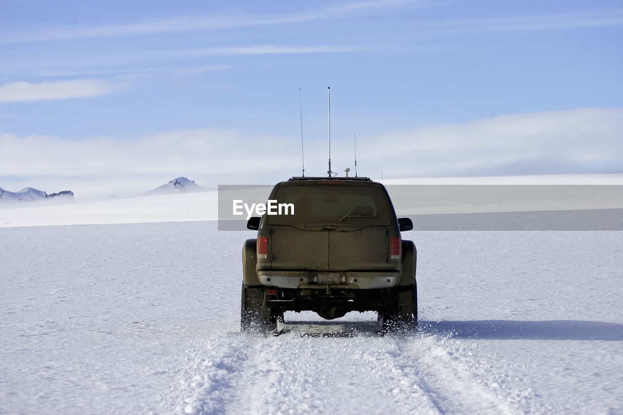 Customised suv ploughing through snowy landscape on icelandic glacier