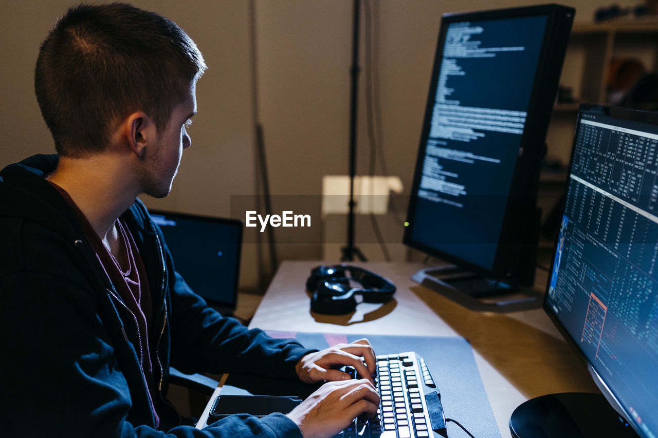 Male hacker looking at computer while working at office