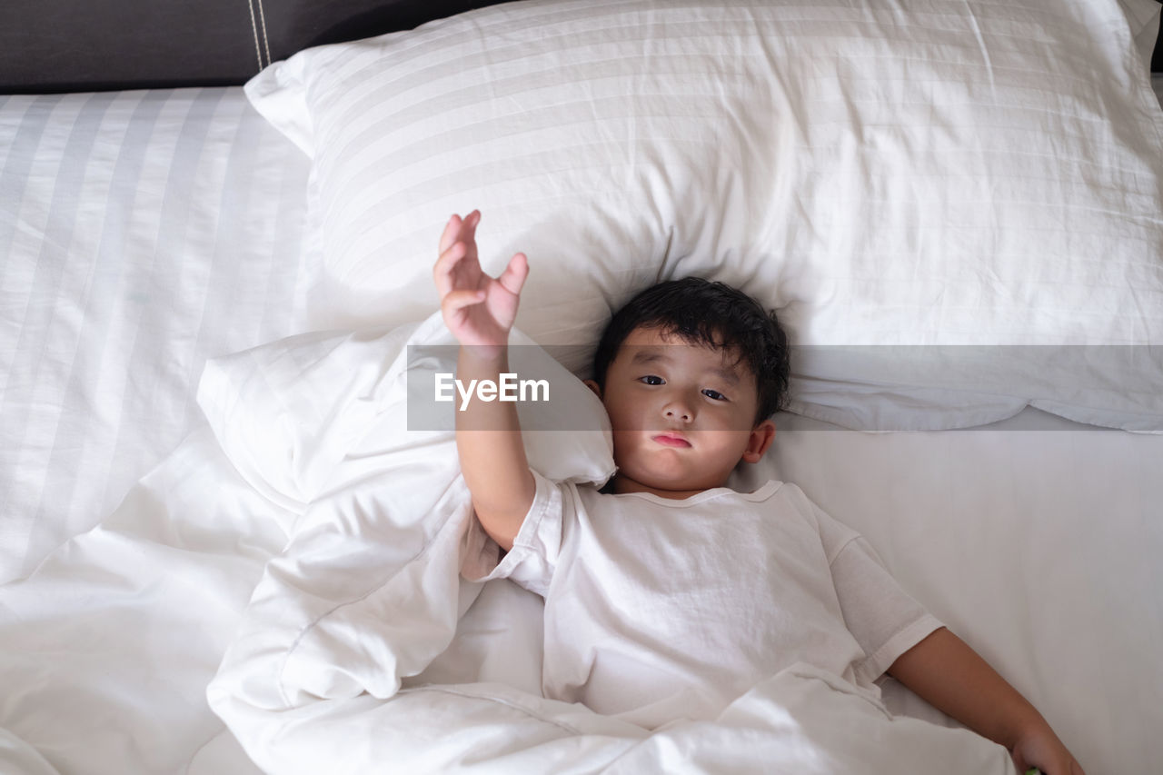 High angle portrait of cute boy lying on bed at home