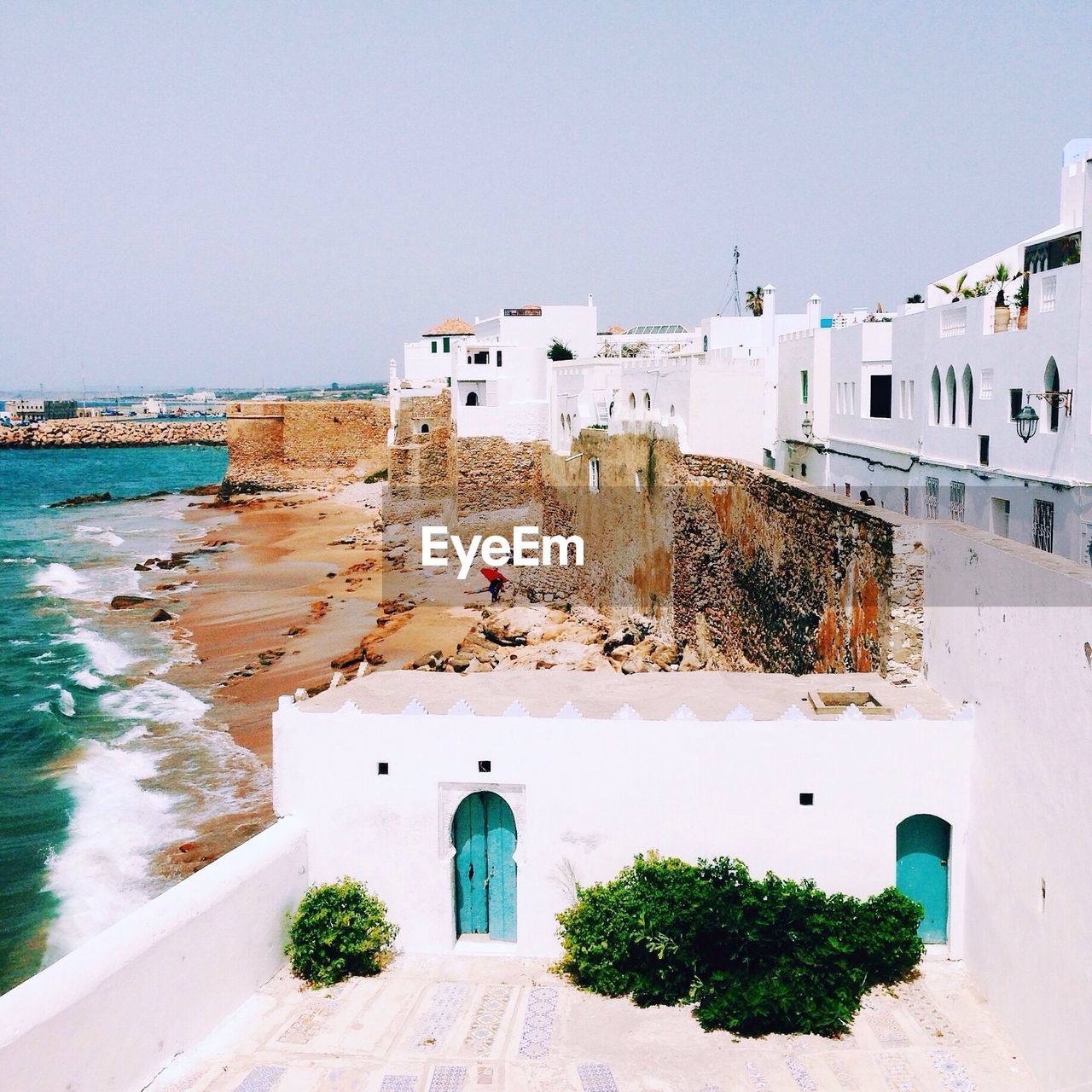 Buildings by sea against sky