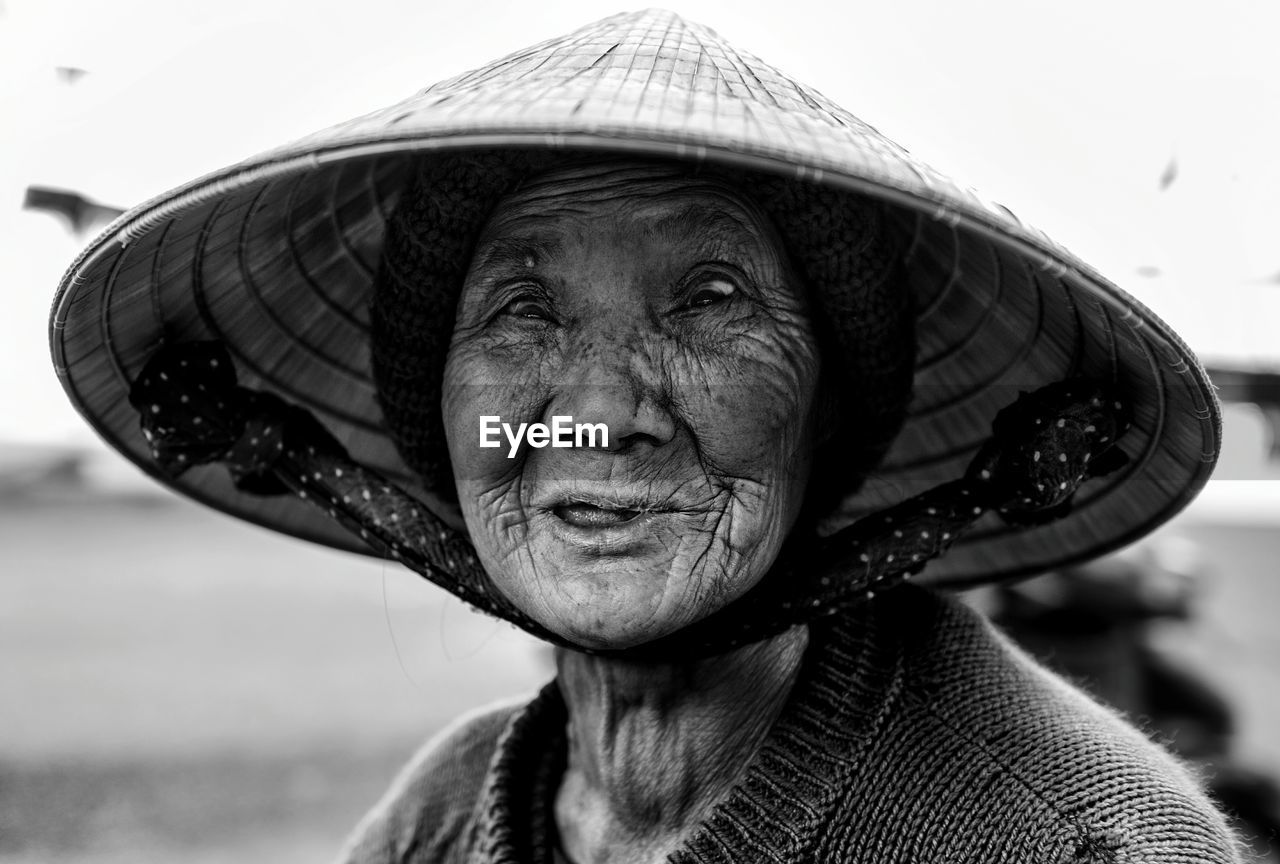 Close-up portrait of senior woman wearing asian style conical hat