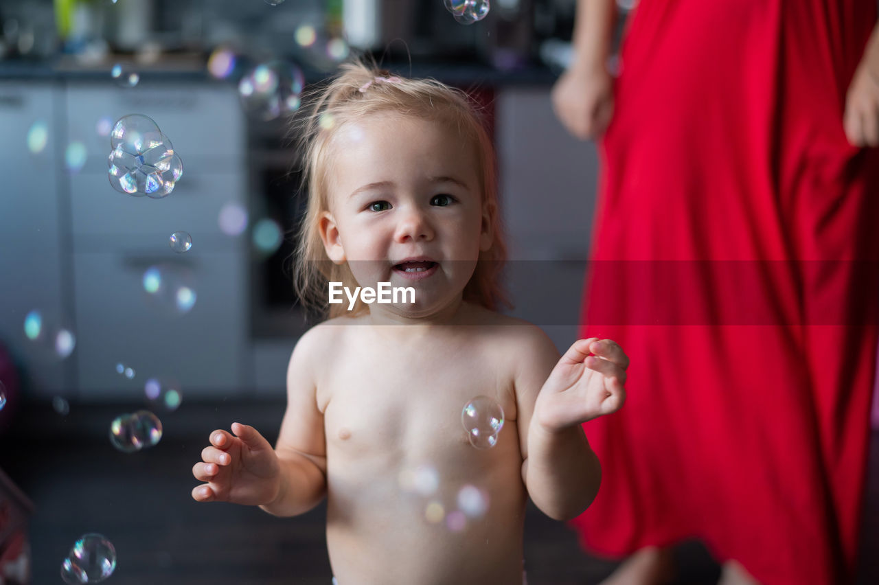 Portrait of shirtless boy looking at bubbles