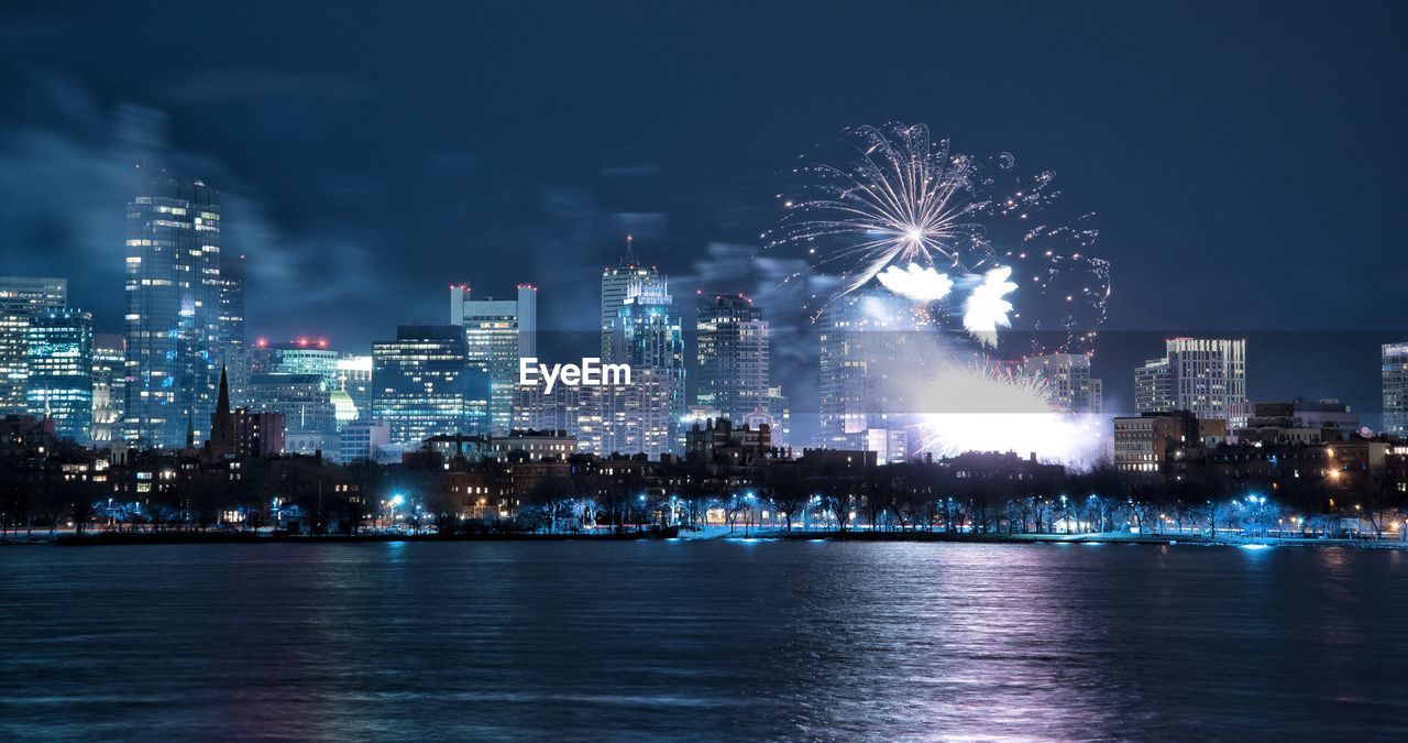Firework display over city by river at night
