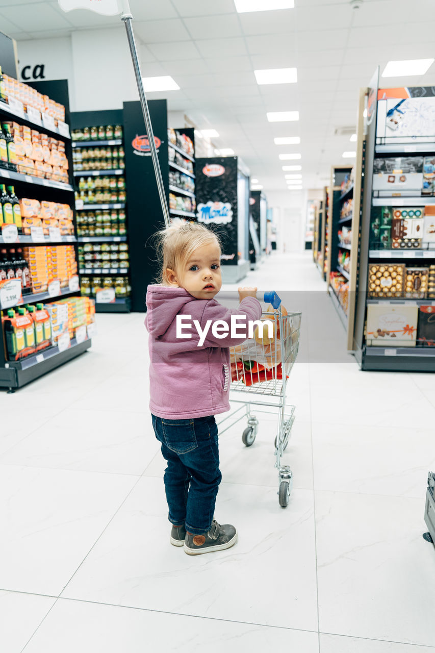 FULL LENGTH OF BOY STANDING BY STORE