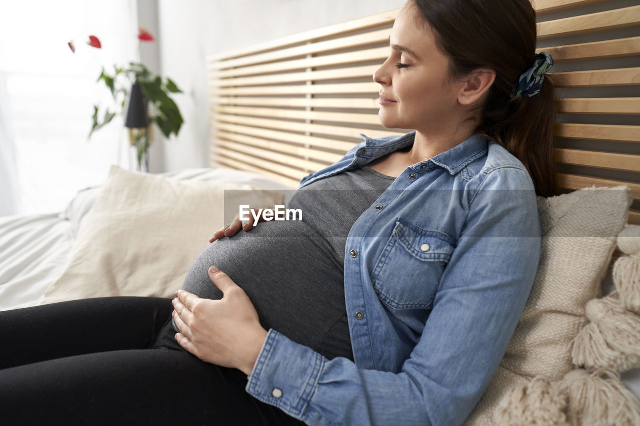 Pregnant woman resting on bed at home