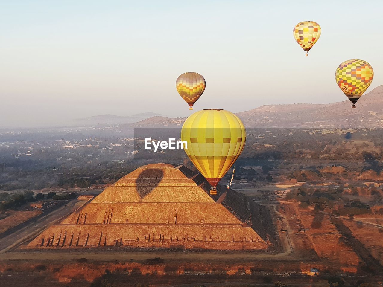 Hot air balloons flying over ancient pyramid