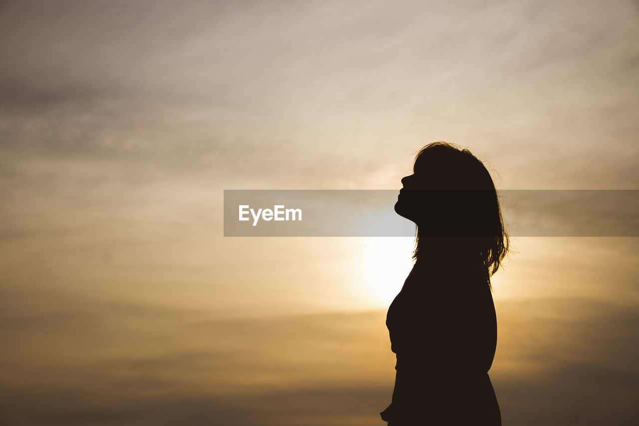 Silhouette woman standing against sky during sunset