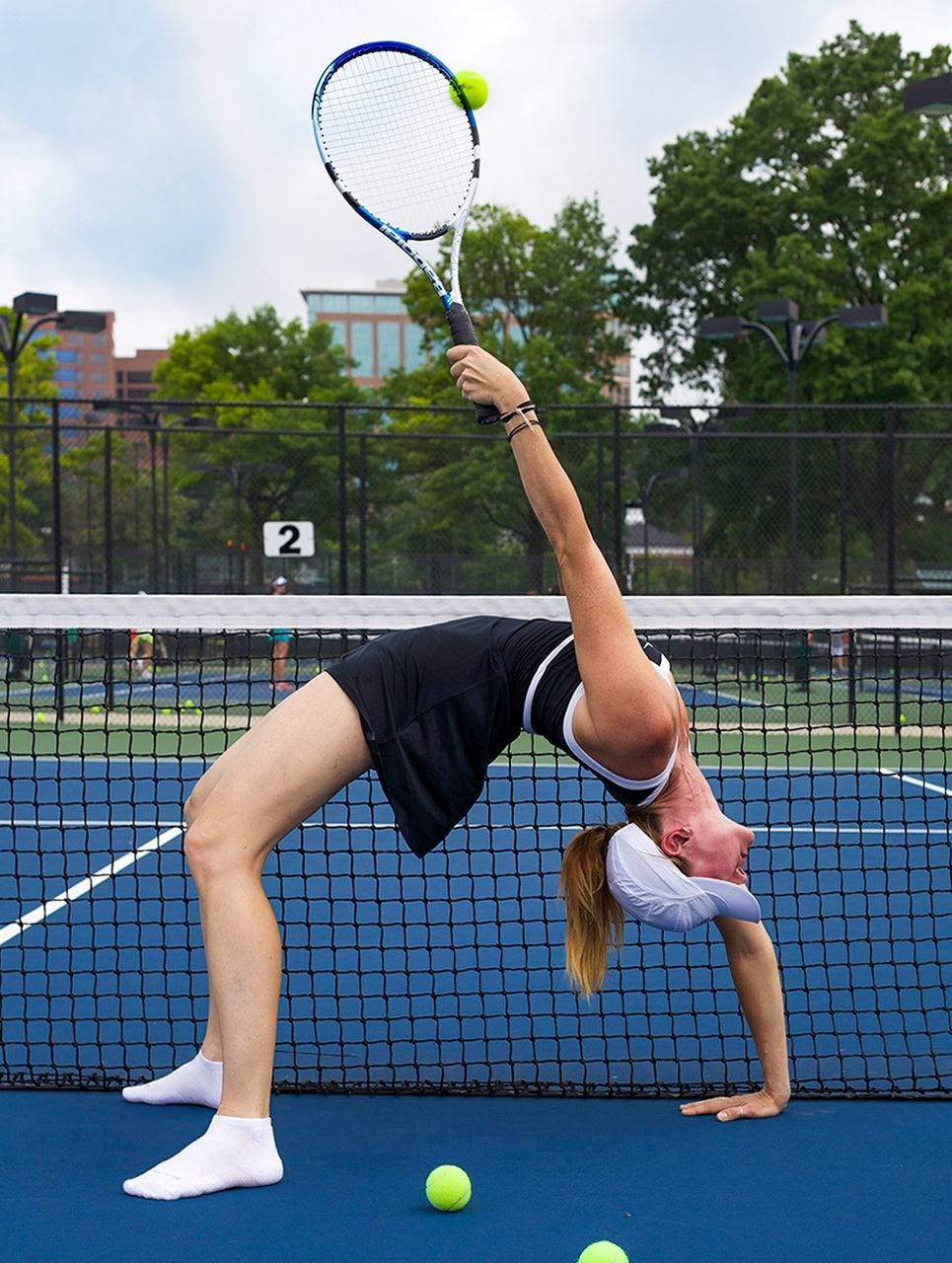 Female player doing backbend while playing tennis in court