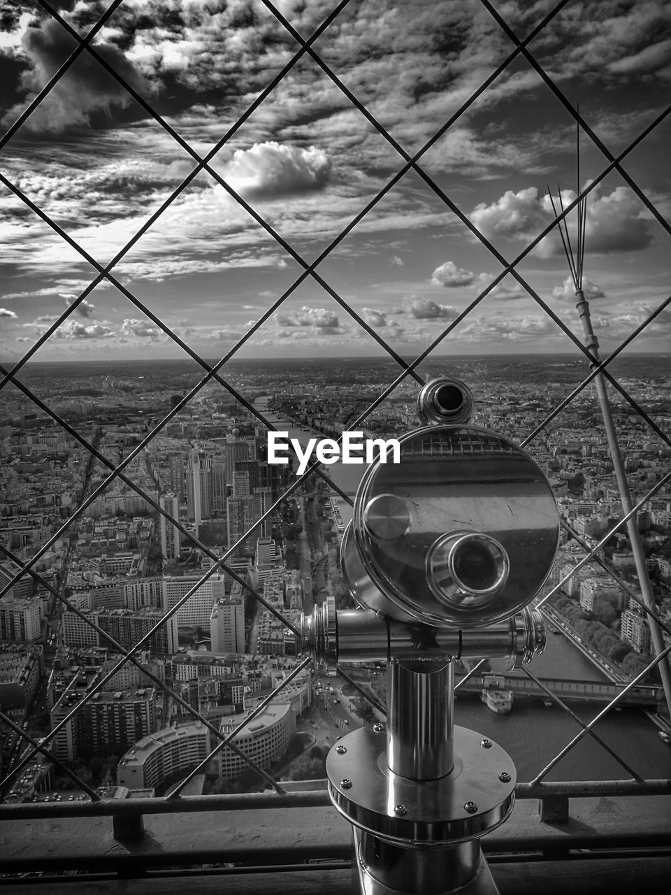 Coin operated binoculars overlooking cityscape against cloudy sky