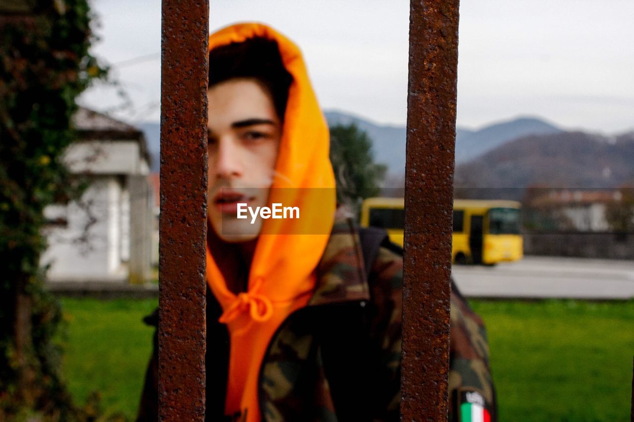 Portrait of man by gate against sky