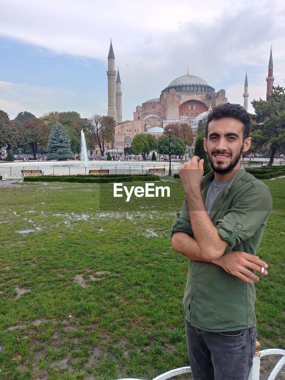 Portrait of smiling young man standing against historic mosque