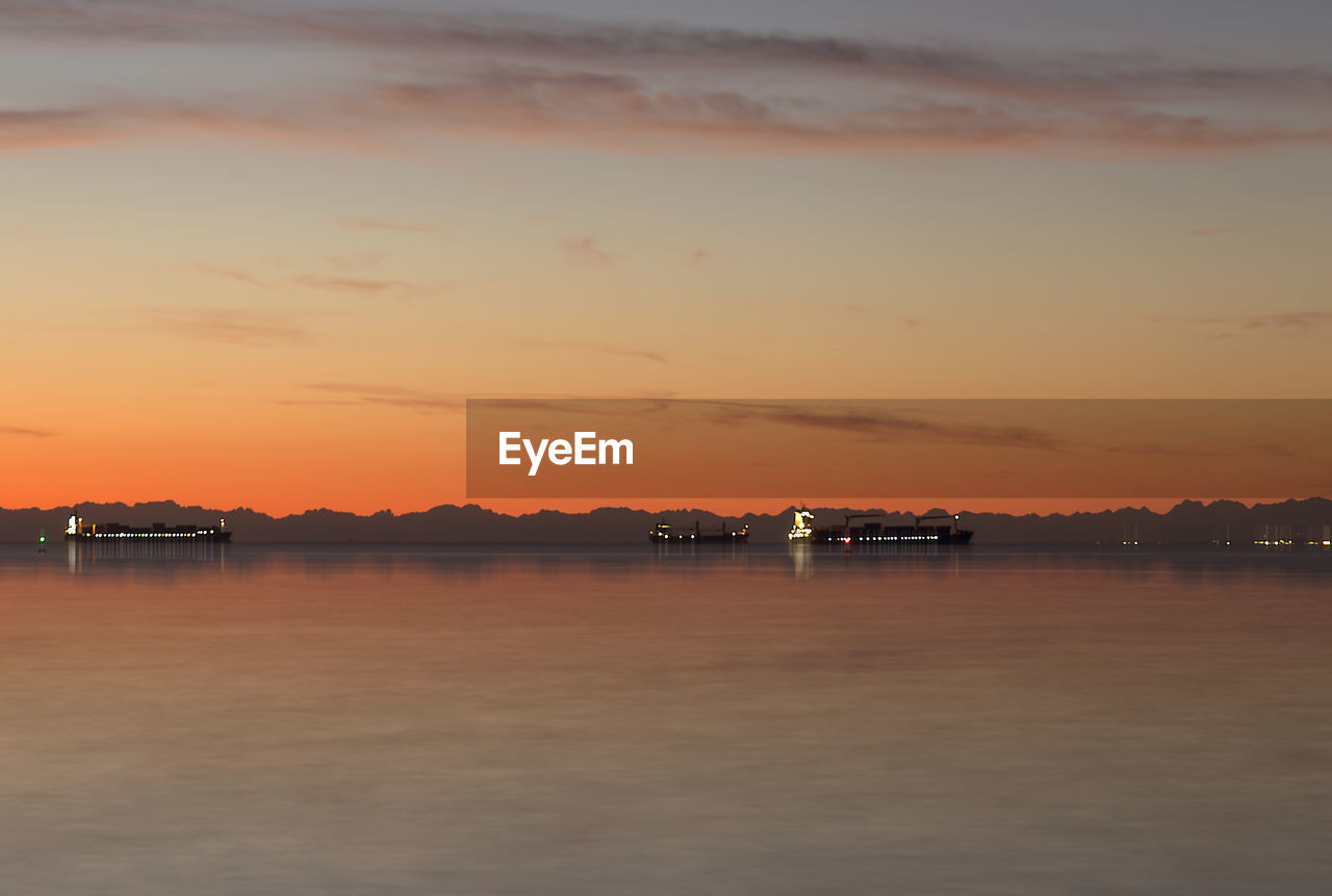 Boats in sea at sunset