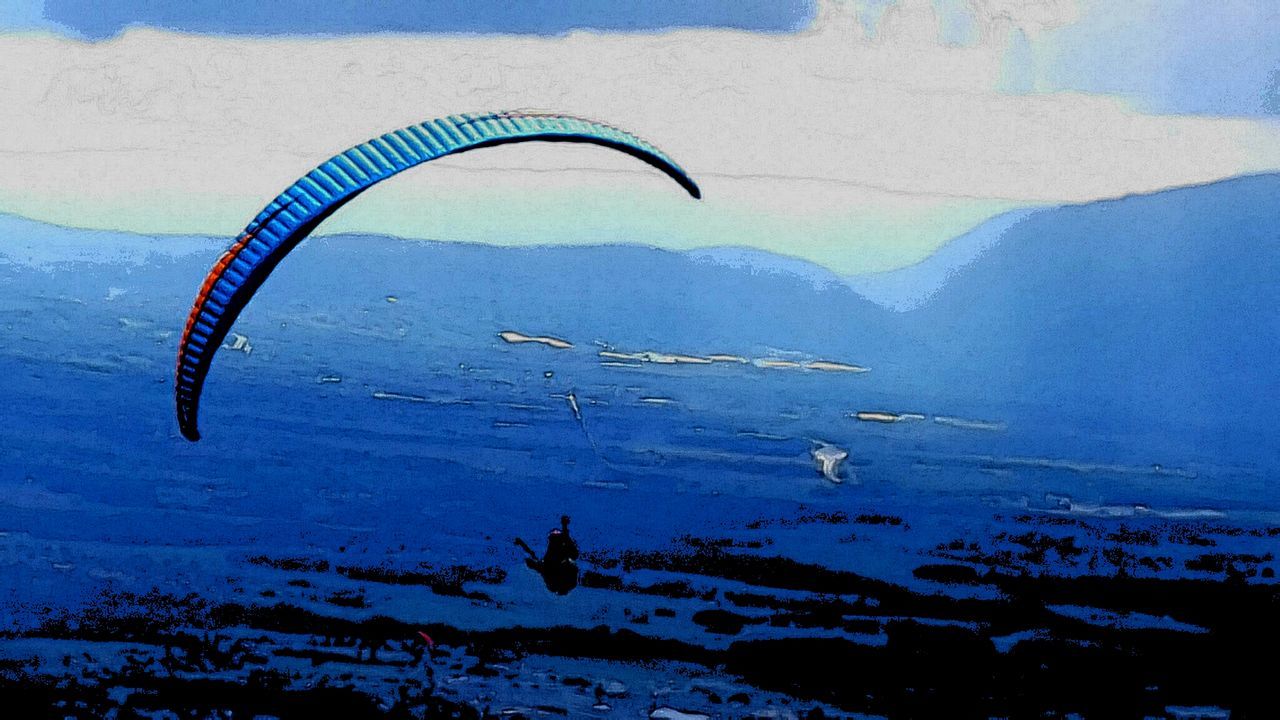 PERSON PARAGLIDING OVER MOUNTAINS