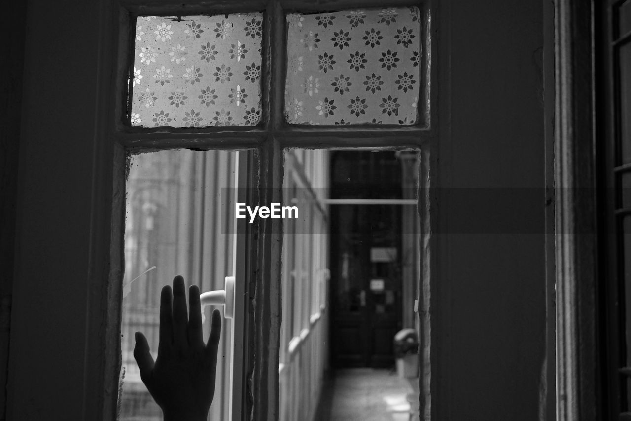 Cropped hand touching window at home