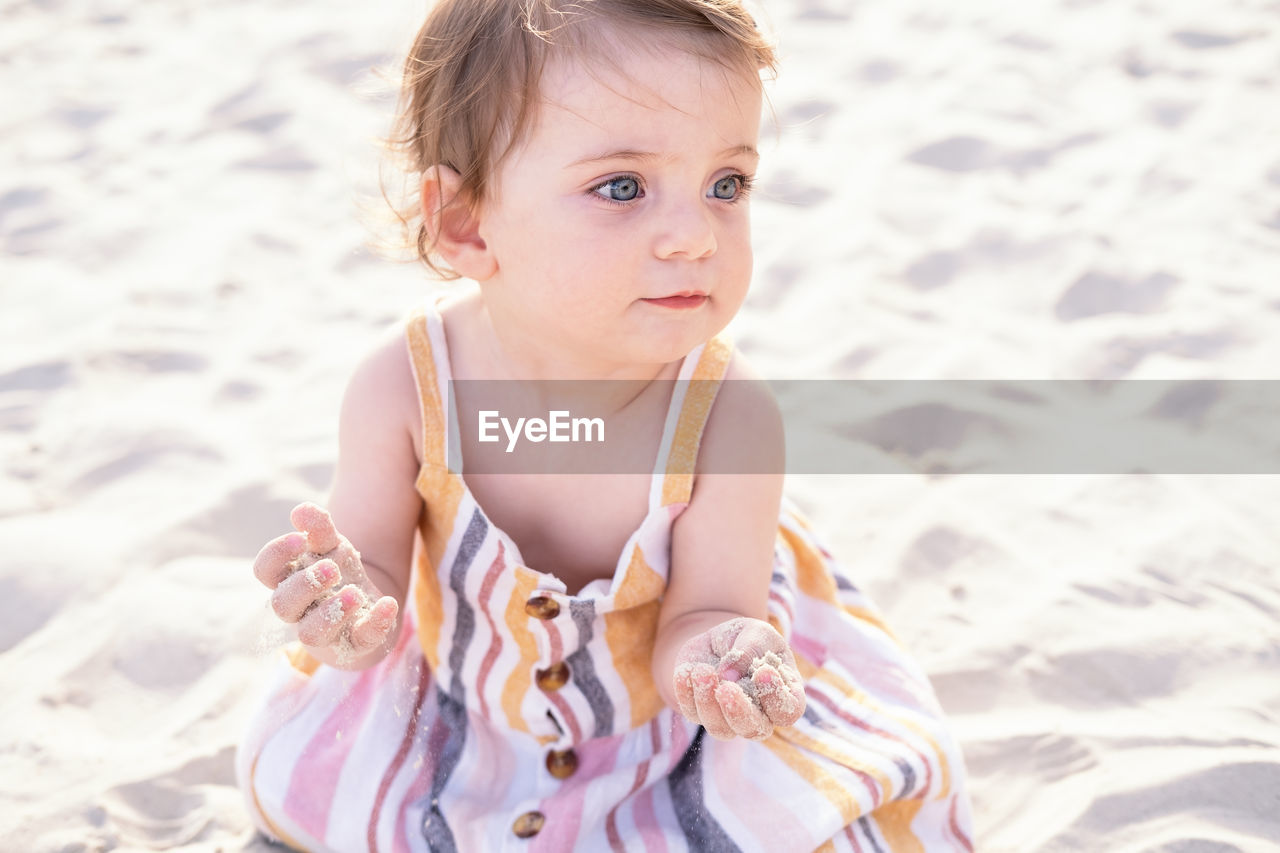 portrait of cute girl playing with arms raised at beach