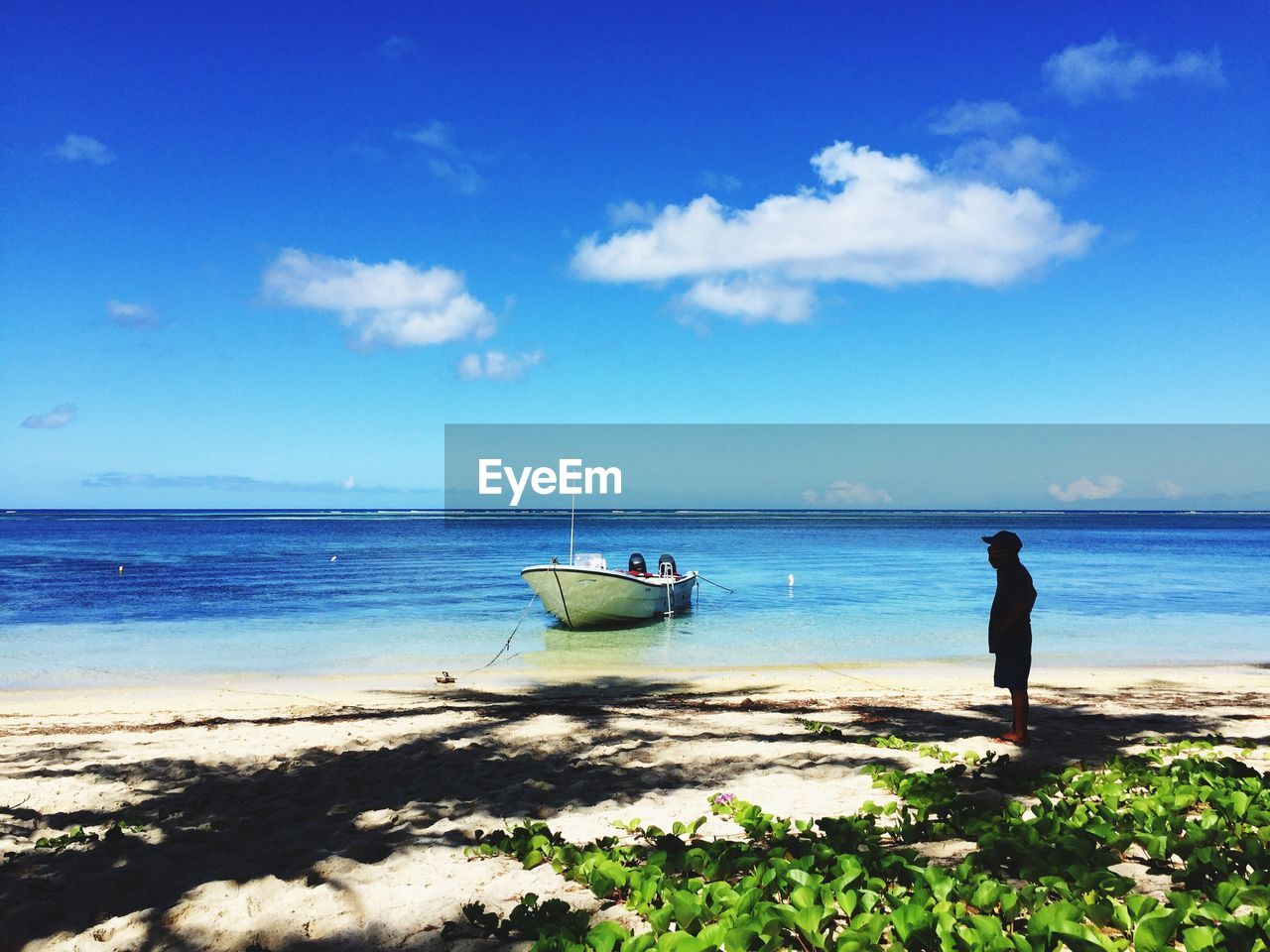 Man standing on beach next to boat