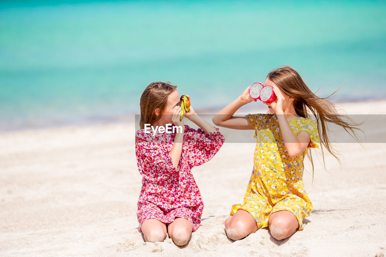 REAR VIEW OF GIRL ON BEACH AGAINST SEA