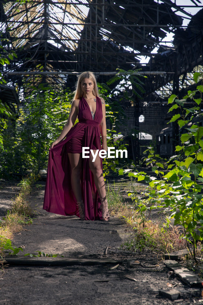 Portrait of woman standing by plants in abandoned train yard