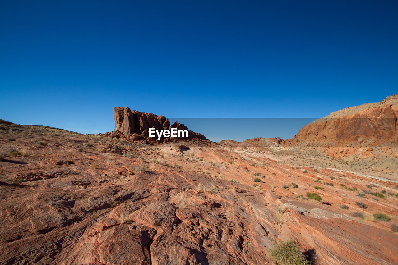 Rock formations on landscape against clear blue sky