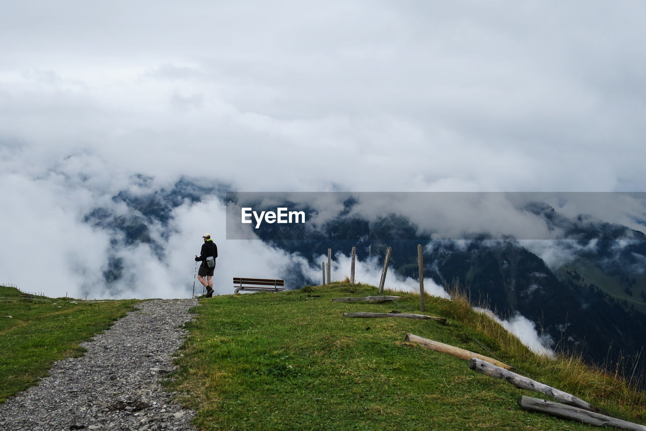 MAN WALKING ON MOUNTAIN AGAINST SKY