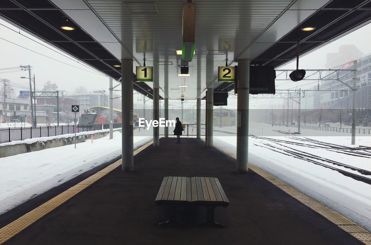 Woman standing in railroad station during winter