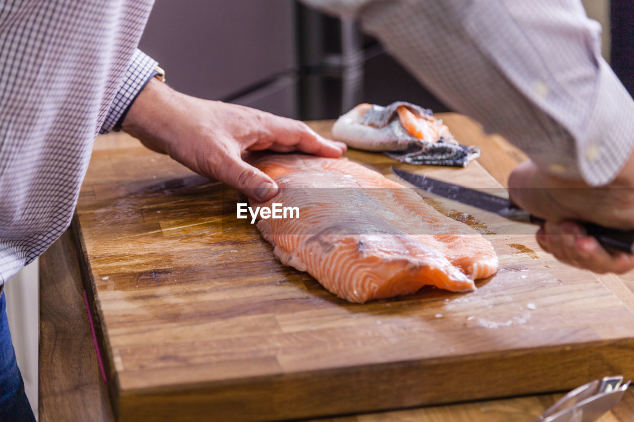 Cropped image of man cutting fish