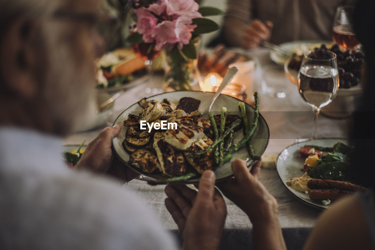 Man passing food plate to woman while sitting at dining table during party