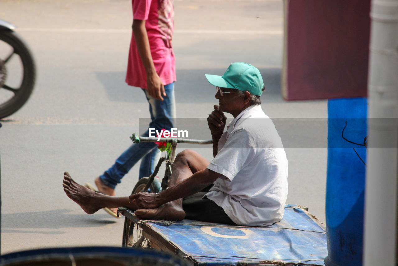 SIDE VIEW OF PEOPLE SITTING IN STREET