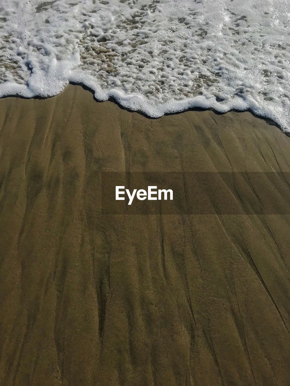 High angle view of surf reaching on shore at beach