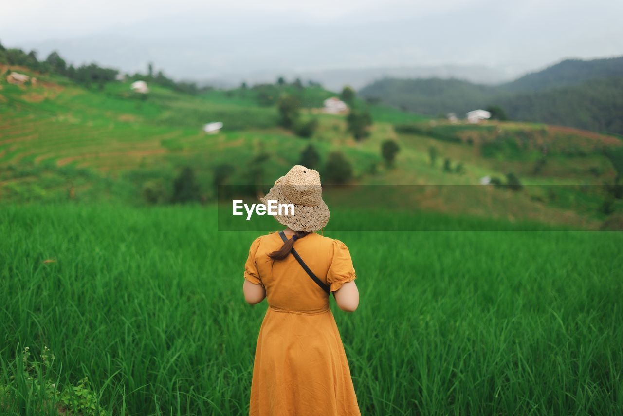 REAR VIEW OF WOMAN WITH HAT ON FIELD